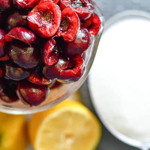 Cherry jam ingredients including cherries, sugar, and lemon juice.