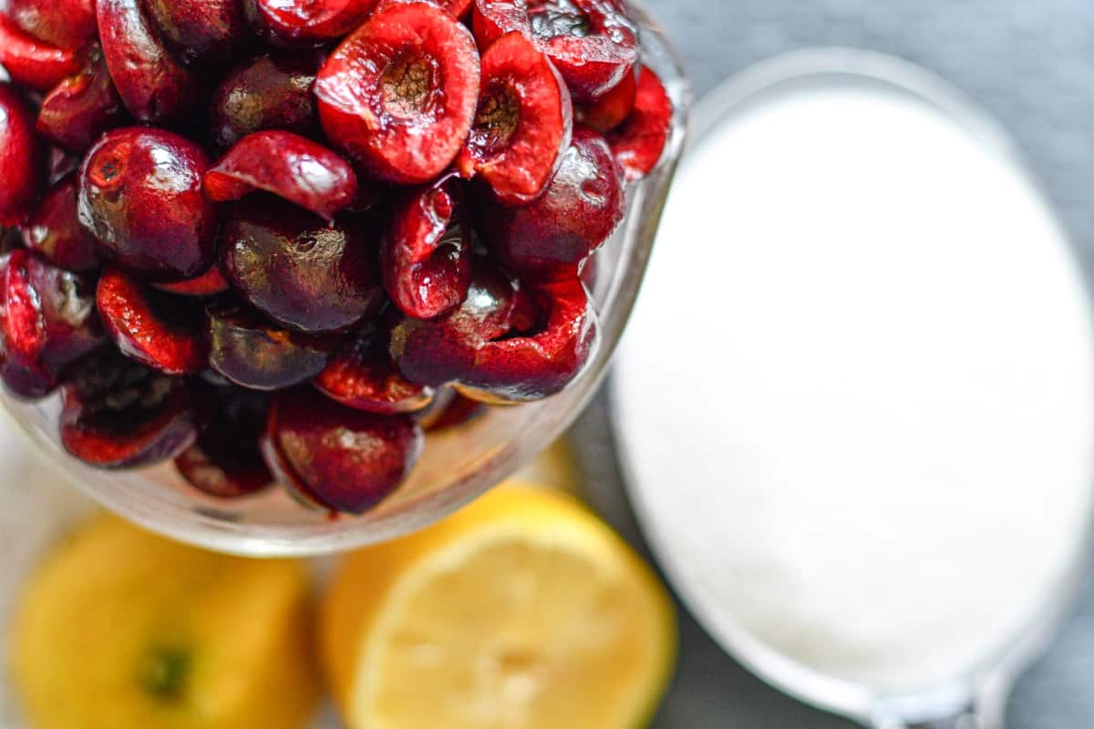 Cherry jam ingredients including cherries, sugar, and lemon juice.