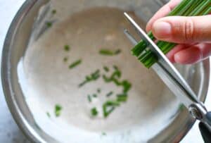 Cutting chives into homemade blue cheese dressing