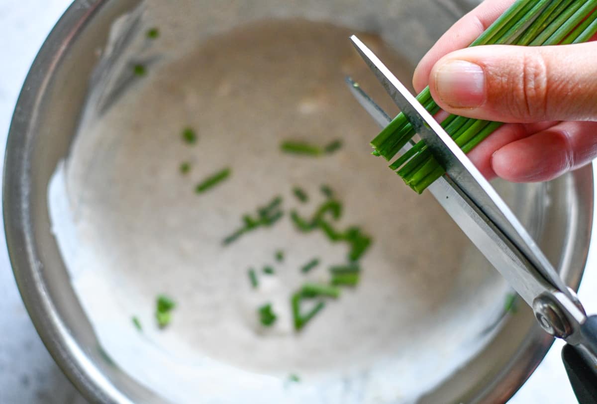 Cutting chives into homemade blue cheese dressing