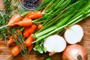 Yellow onion, carrots, celery, fresh thyme, fresh rosemary, bay leaves, and juniper berries for making smoked deer trotter broth.