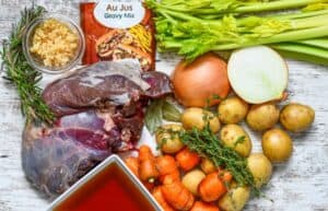 Deer Pot Roast Ingredients including carrots, celery, baby potatoes, onion, minced garlic, fresh rosemary, fresh thyme, beef broth, and Au Jus gravy mix