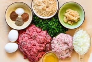 Venison Swedish Meatball Ingredients including ground venison, ground pork, eggs, onion, minced garlic, panko breadcrumbs, fresh spinach, salt, black pepper, allspice, and nutmeg