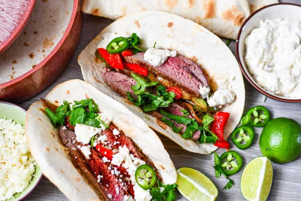 Deer Fajitas with onion, peppers, cilantro, queso fresco, limes, jalapenos, all on flour tortillas.