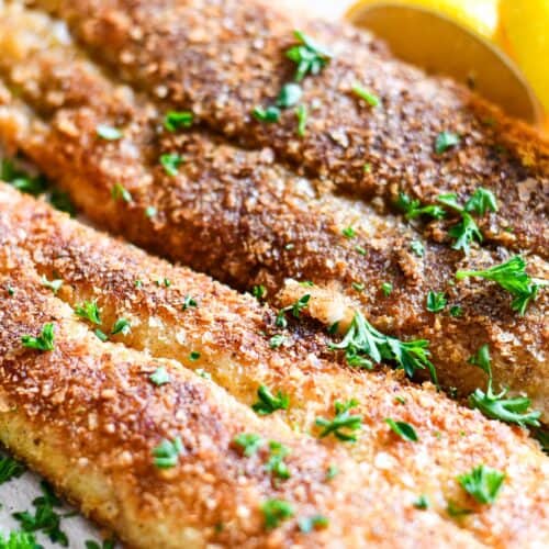 Potato Crusted Fish garnished with lemon wedges and chopped fresh parsley.