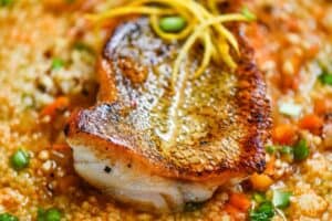 Fish Soup Recipe topped with pan seared walleye and garnished with fresh chives and lemon zest