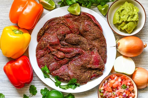 Snow Goose Fajitas Ingredients including goose breast, onion, bell peppers, lime, cilantro, guacamole, and pico de gallo.