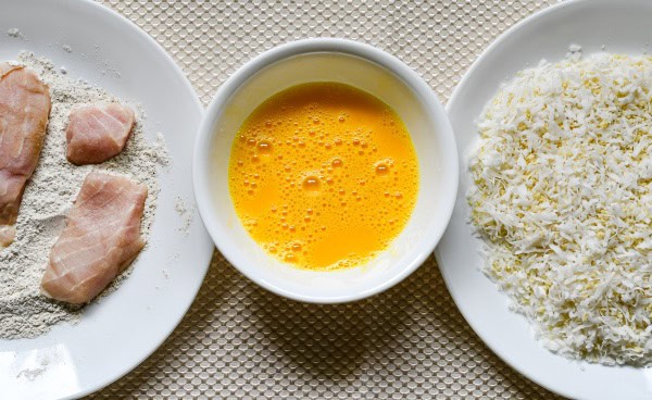 Dredging station including American Paddlefish fillets in seasoned flour, egg, and shredded coconut panko breadcrumb mix.