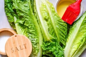 Grilled Caesar Salad ingredients including romaine lettuce hearts, olive oil, and kosher salt