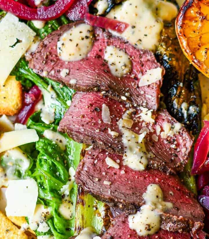 Steak Caesar Salad with grilled romaine lettuce, croutons, parmesan, pickled onion, lemon, and venison steak