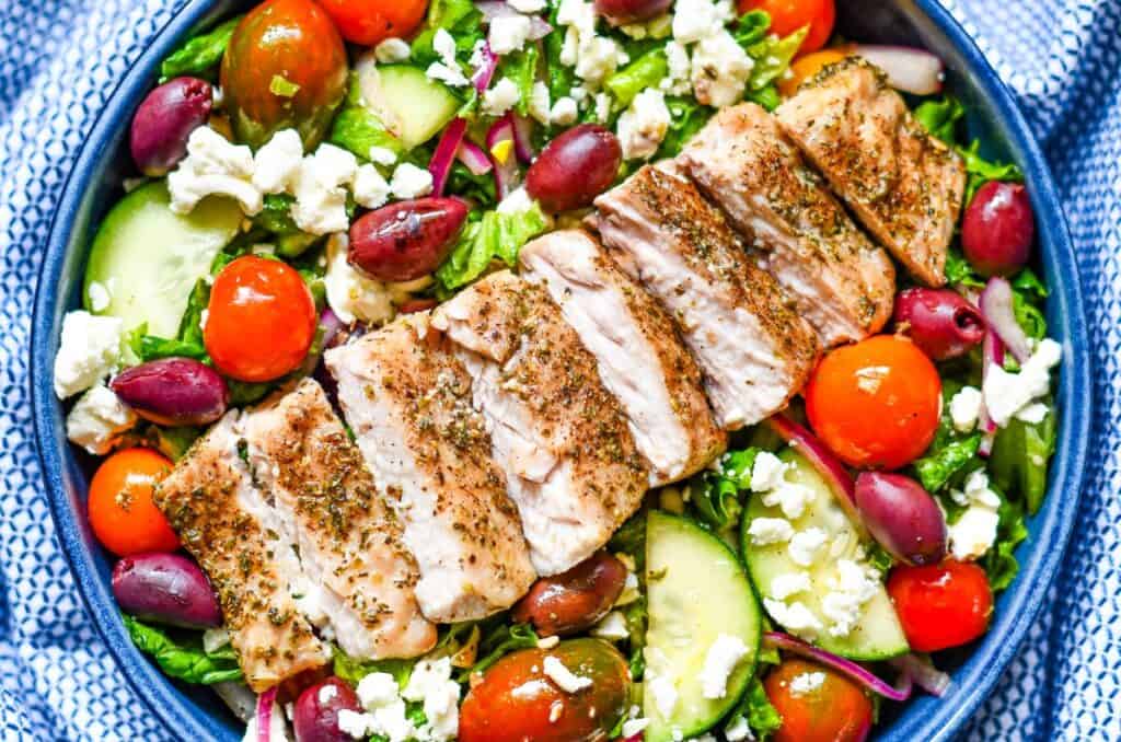 Mediterranean Fish Salad using baked Paddlefish with green leaf lettuce, cucumbers, cherry tomatoes, kalamata olives, red onion, and feta cheese