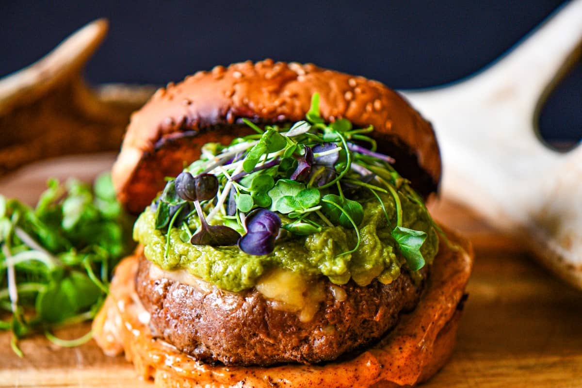 Tex Mex Big Game Burger topped with cheese, guacamole, microgreens, and Tex Mex mayonnaise